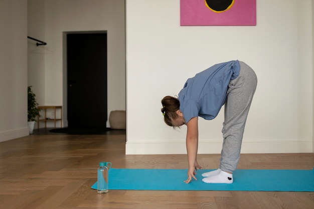 Chica haciendo posturas de yoga vista lateral