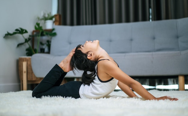 Chica haciendo yoga en la habitación sobre una alfombra blanca. Enfoque selectivo.