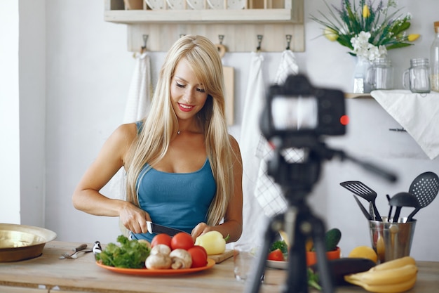 Chica hermosa y deportiva en una cocina grabando un video