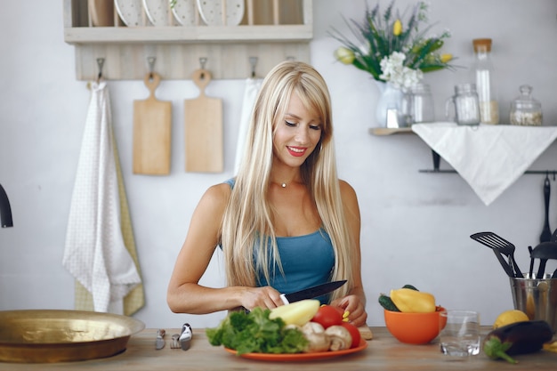 Chica hermosa y deportiva en una cocina con verduras