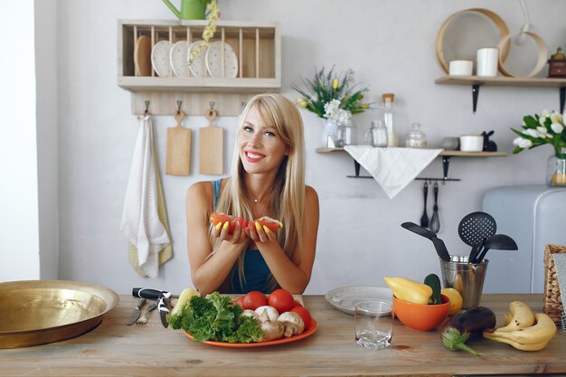 Chica hermosa y deportiva en una cocina con verduras