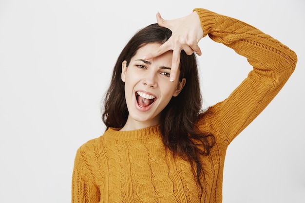 Chica hermosa despreocupada y atrevida mostrando el signo de la paz y sonriendo