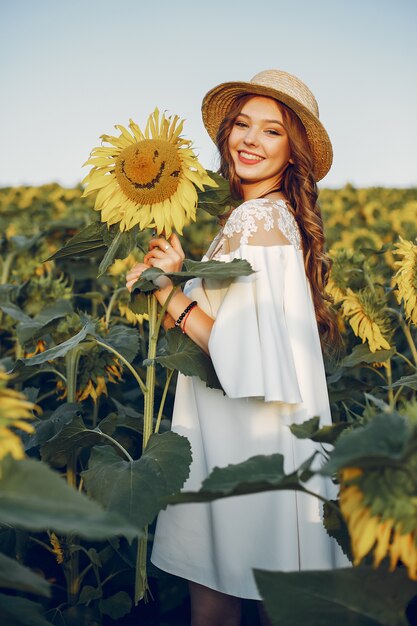 Chica hermosa y elegante en un campo con girasoles