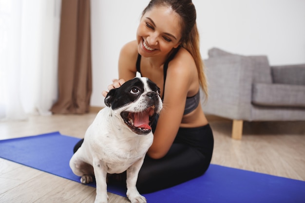 Chica hermosa fitness sentado en el piso con perro