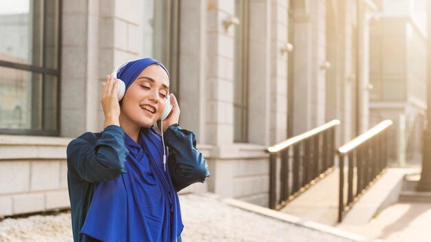 Chica con hijab escuchando música a través de auriculares