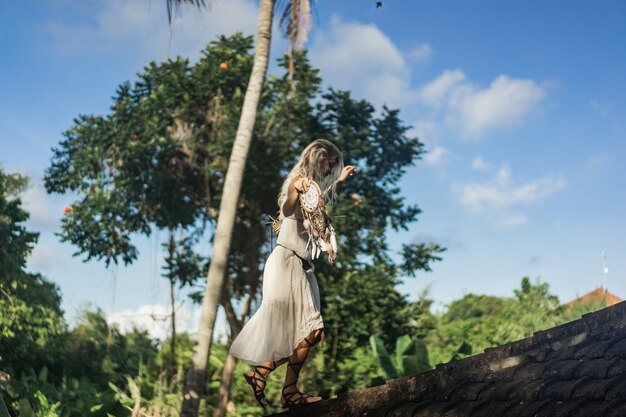 Chica hippie con el pelo largo y rubio en un vestido en el techo.