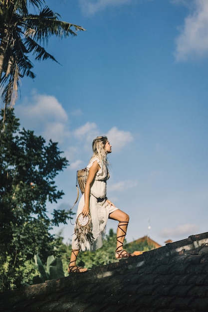 Chica hippie con el pelo largo y rubio en un vestido en el techo.