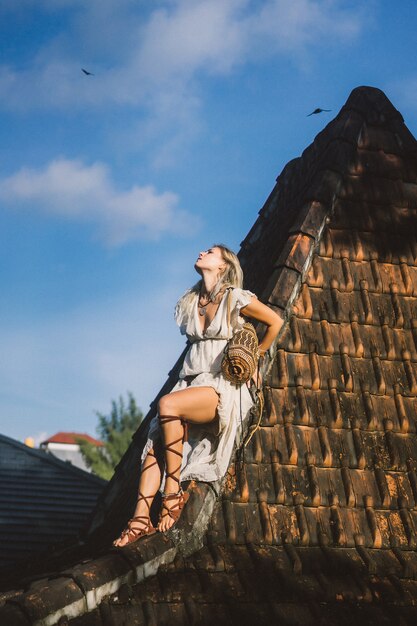 Chica hippie con el pelo largo y rubio en un vestido en el techo.