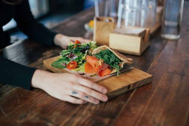 Foto gratuita chica hipster come sándwich de salmón en pita griego