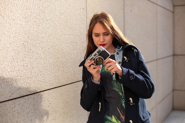 Chica hipster feliz haciendo fotos con cámara retro en la calle de la ciudad. concepto de viaje
