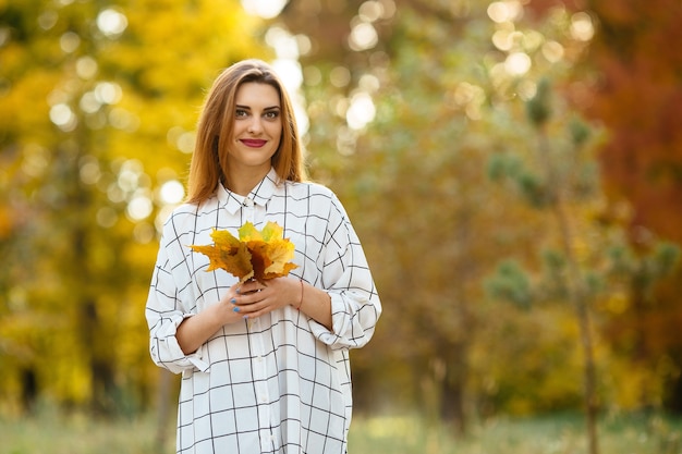 Chica con hojas de otoño en el parque.