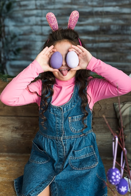 Foto gratuita chica con huevos de pascua mostrando lengua