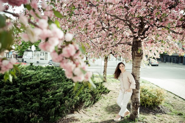 Chica se inclina hacia una sakura en el parque