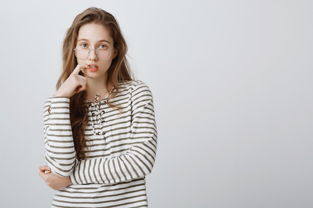 Chica inteligente reflexiva en gafas mirando determinada