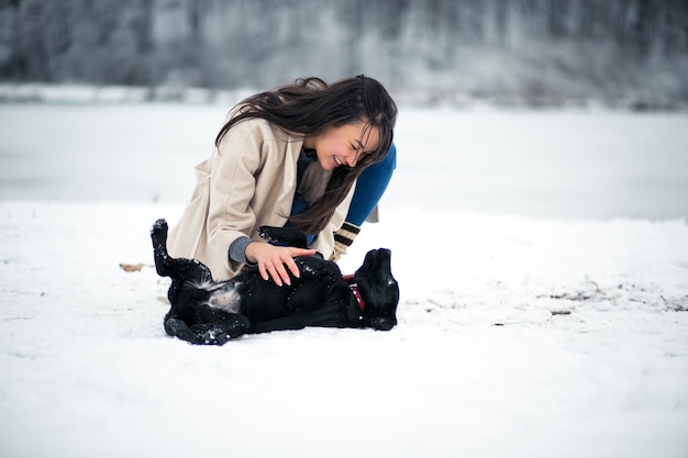 Chica en invierno jugando con perro