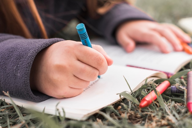 Chica irreconocible doodling en el cuaderno