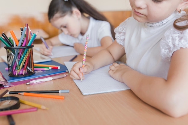 Chica irreconocible escribiendo en cuadernos