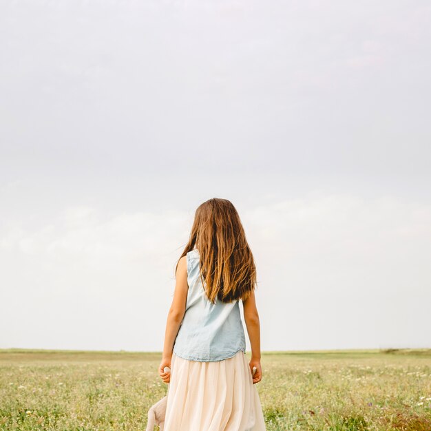 Chica irreconocible de pie en el campo