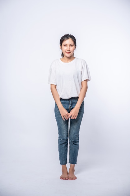 Chica en jeans elásticos blancos y de pie sobre una superficie blanca.