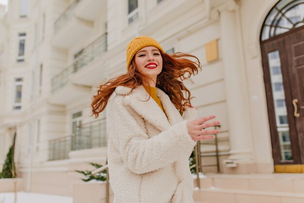 Chica de jengibre inspirada bailando en la calle. Señora caucásica entusiasta divirtiéndose en invierno.