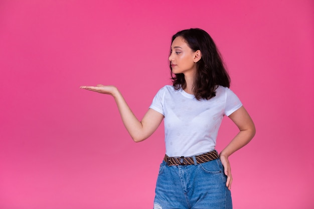 La chica joven abre la mano y presenta algo.