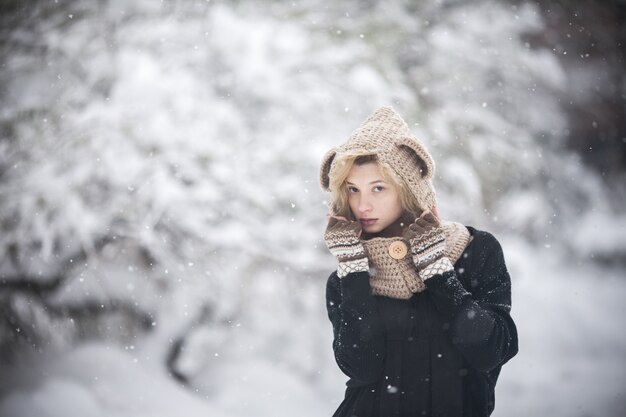 Chica joven abrigada en la nieve con fondo desenfocado