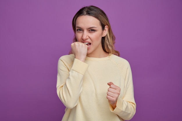 Chica joven agresiva mordiendo el puño