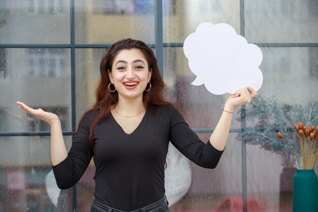 Chica joven alegre sosteniendo burbuja de idea y riendo