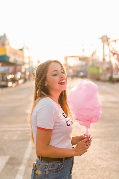 Chica joven con algodón de azúcar en el parque de atracciones