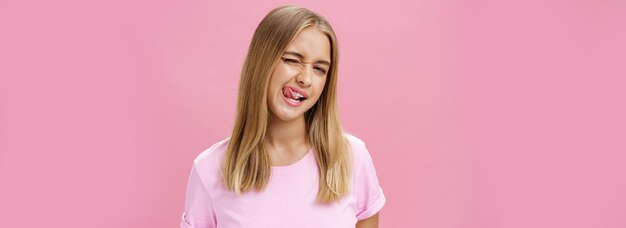 Foto gratuita chica joven atractiva y juguetona con el cabello liso y claro en camiseta guiñando el ojo a la cámara sonriendo y