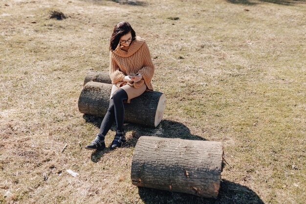 Chica joven y atractiva en la naturaleza en el fondo del bosque con teléfono en un día soleado