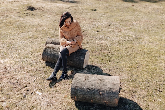 Chica joven y atractiva en la naturaleza en el fondo del bosque con teléfono en un día soleado