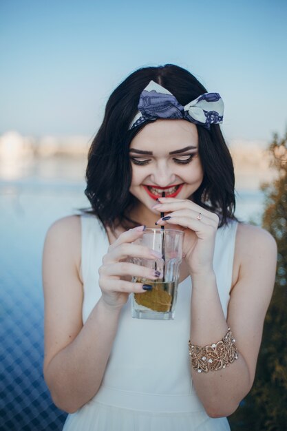 Chica joven bebiendo de un vaso mientras sonríe