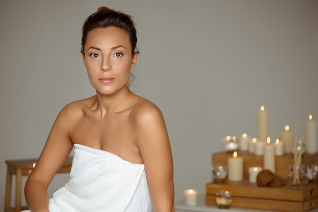 Chica joven y bella relajante en el salón de spa.