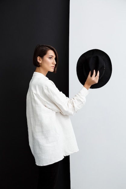 Foto gratuita chica joven y bella con sombrero sobre pared blanco y negro