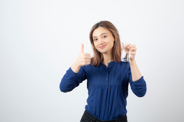 Foto gratuita chica joven en blusa azul sosteniendo agua y dando pulgares.