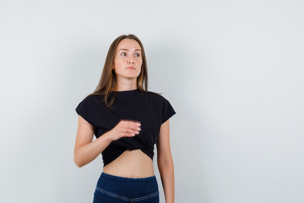 Chica joven en blusa negra, pantalones mirando a otro lado y mirando enfocado