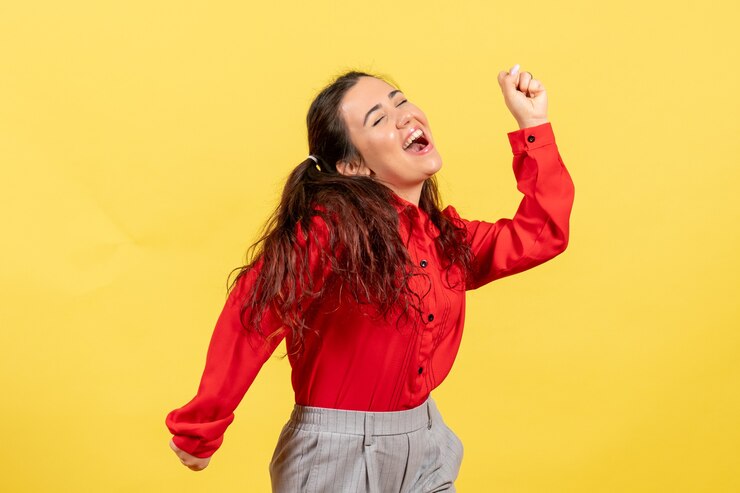 Foto gratuito chica joven en blusa roja bailando sobre amarillo