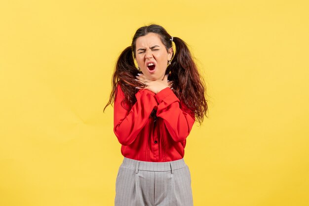 Chica joven en blusa roja con dolor de garganta en amarillo