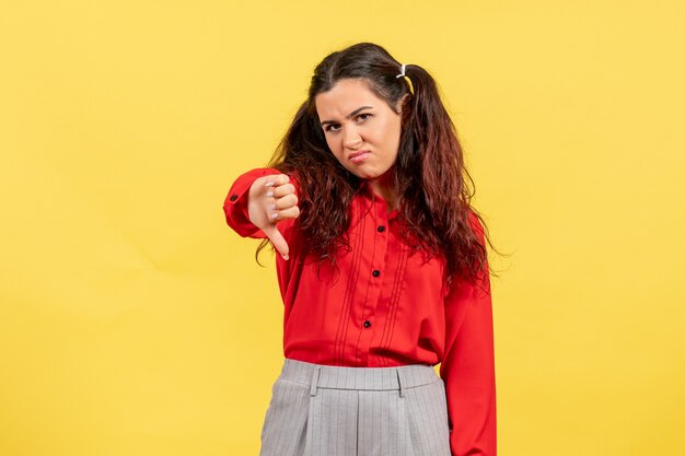 Chica joven en blusa roja mostrando signo diferente en amarillo