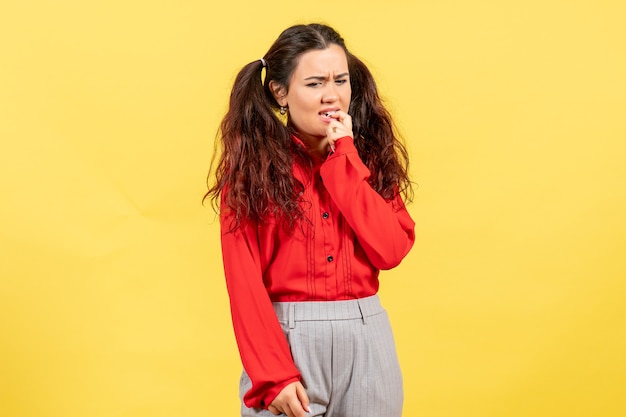 Chica joven en blusa roja pensando nerviosamente en amarillo