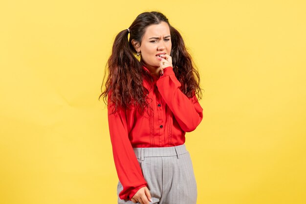 Chica joven en blusa roja pensando nerviosamente en amarillo