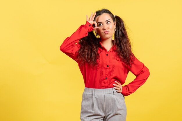 chica joven en blusa roja posando en amarillo