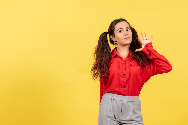 chica joven en blusa roja posando en amarillo