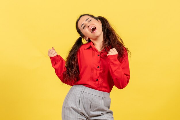 Chica joven en blusa roja en pose de baile en amarillo