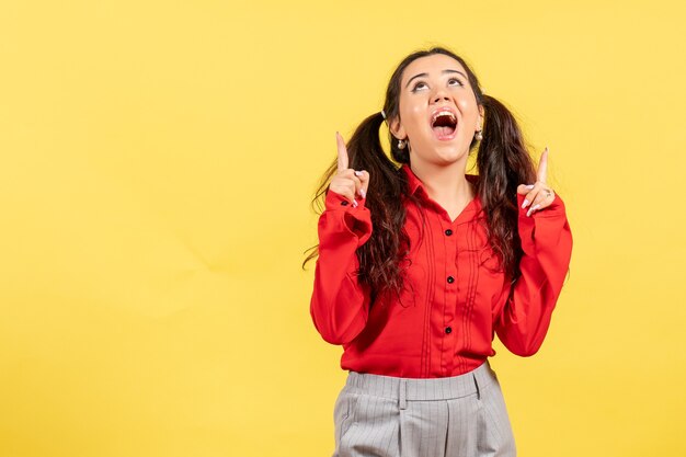 Chica joven en blusa roja sintiéndose emocionada en amarillo