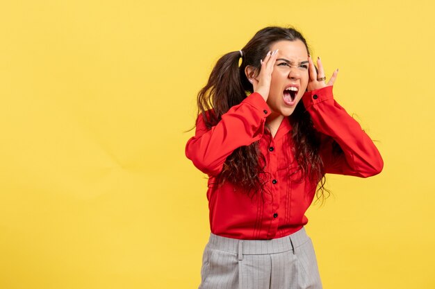 Chica joven en blusa roja sintiéndose enojada en amarillo