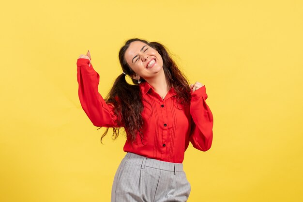 Chica joven en blusa roja sintiéndose feliz en amarillo