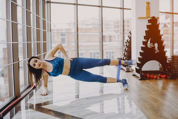 chica joven y bonita en un traje azul se dedica a deportes en el gimnasio