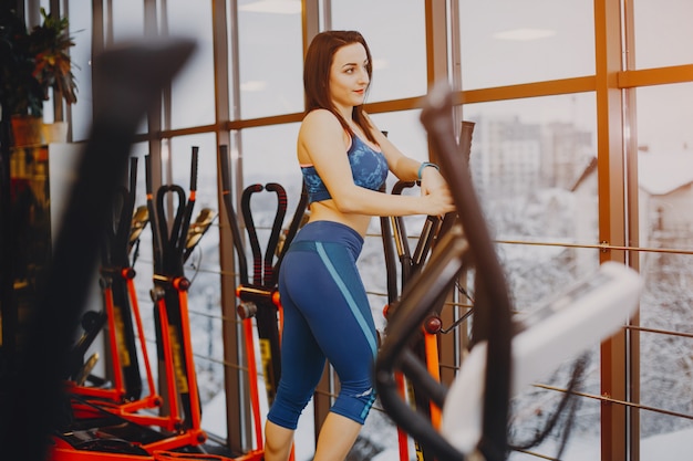 chica joven y bonita en un traje azul se dedica a deportes en el gimnasio